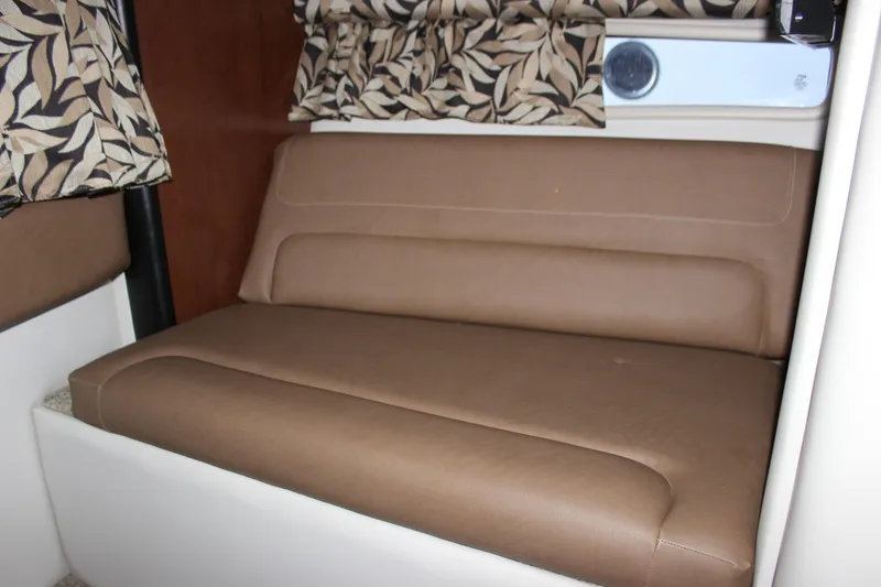 Slide: The Image of 2021 Crownline 294 CR cabin interior with brown leather seating and patterned curtains. - 28