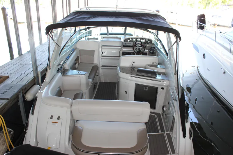 Slide: The Image of 2021 Crownline 294 CR boat interior with seating, helm, and canopy in marina. - 6