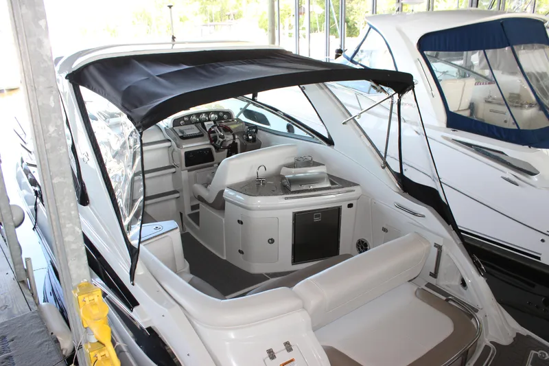 Slide: The Image of 2021 Crownline 294 CR boat interior with seating, helm, and canopy in marina. - 8