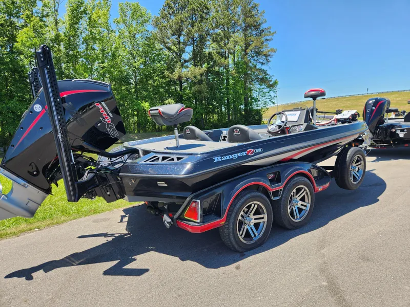 Slide: The Image of 2022 Ranger Z519 boat on trailer, parked on road, surrounded by trees and grass. - 2