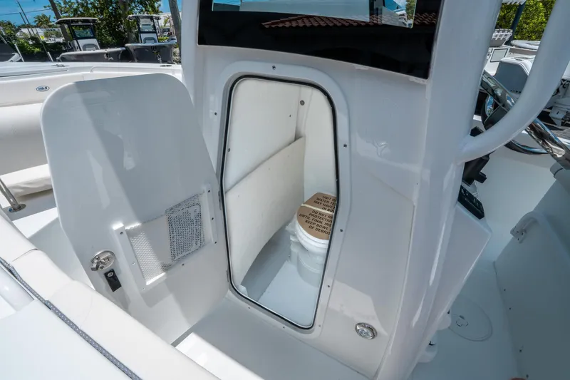 Slide: The Image of 2025 Sea Hunt Ultra 245 SE boat interior with open door revealing compact marine toilet. - 25