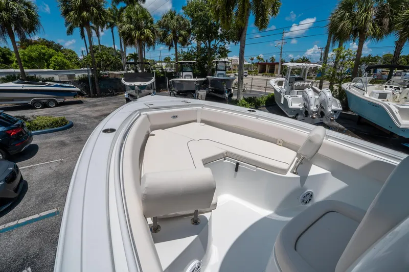 Slide: The Image of 2025 Sea Hunt Ultra 245 SE boat interior with seating, parked under palm trees. - 26