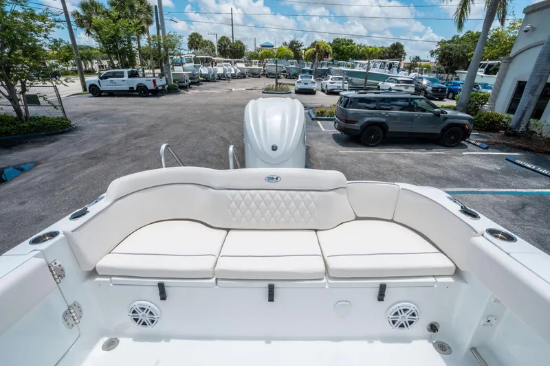 Slide: The Image of 2025 Sea Hunt Ultra 245 SE boat interior with white seating, parked in a lot. - 10