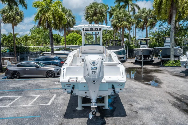 Slide: The Image of 2025 Sea Hunt Ultra 245 SE boat in a sunny marina with palm trees. - 3