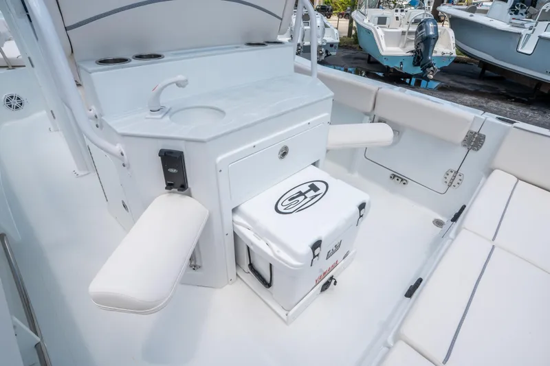 Slide: The Image of 2025 Sea Hunt Ultra 245 SE boat interior with seating, sink, and cooler. - 15
