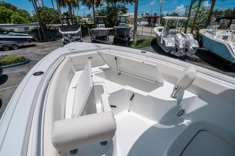 Slide: The Image of 2025 Sea Hunt Ultra 245 SE boat interior with open storage compartments, parked outdoors. - 30