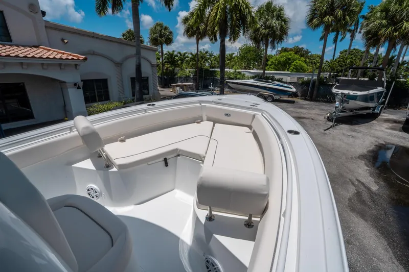 Slide: The Image of 2025 Sea Hunt Ultra 245 SE boat with spacious seating, parked outdoors under palm trees. - 27