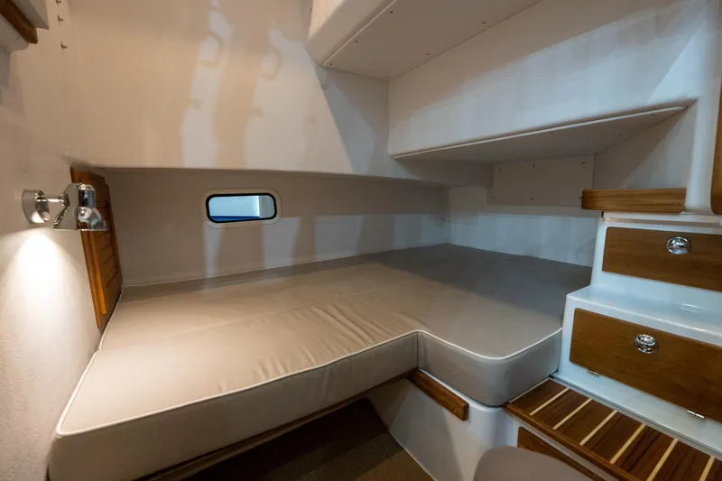 Slide: The Image of 2026 Targa 27 boat cabin with cozy bed, wooden drawers, and small window. - 16
