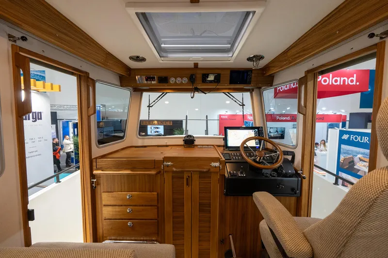 Slide: The Image of Interior of 2026 Targa 27 boat with wooden dashboard and steering wheel at a boat show. - 21
