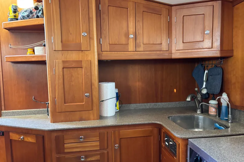 Slide: The Image of Wooden kitchen interior of 1999 Diesel Duck Trawler with cabinets and sink. - 24