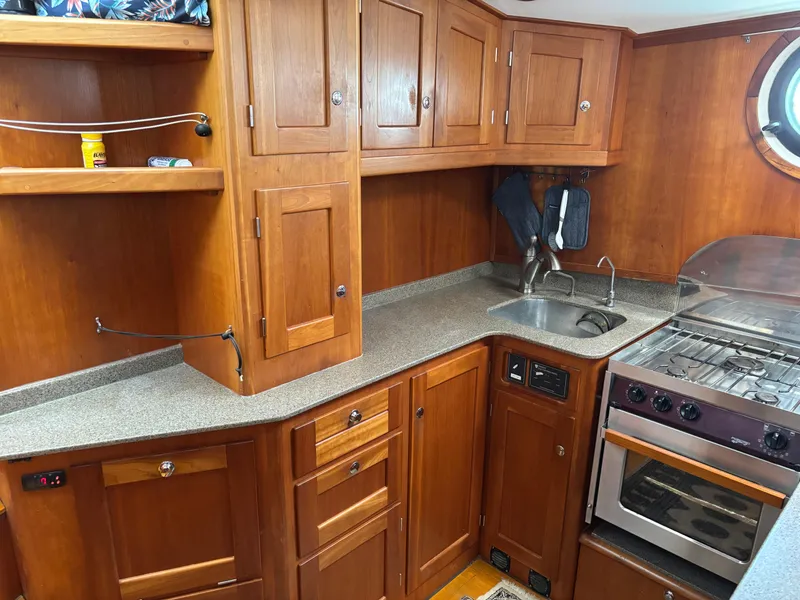 Slide: The Image of 1999 Diesel Duck Trawler kitchen with wooden cabinets, stove, and sink. - 25