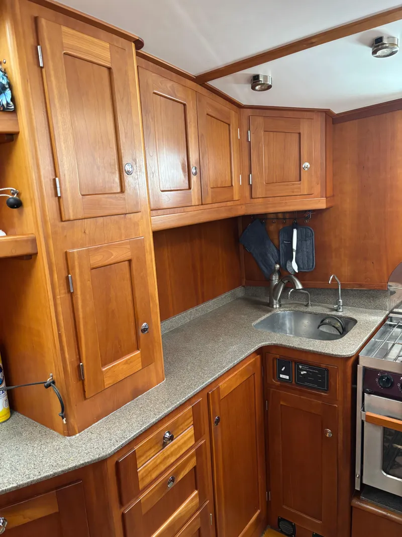 Slide: The Image of 1999 Diesel Duck Trawler kitchen with wooden cabinets and compact sink area. - 26