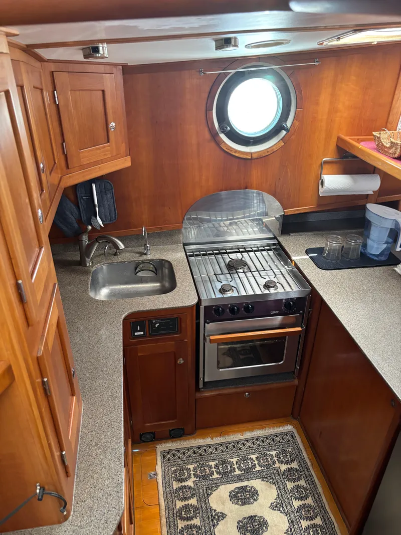 Slide: The Image of 1999 Diesel Duck Trawler kitchen with stove, sink, and wooden cabinetry. - 27