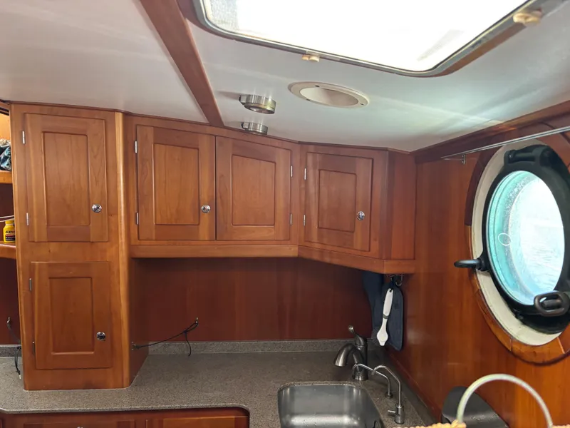 Slide: The Image of Interior of 1999 Diesel Duck Trawler with wooden cabinets and porthole window. - 28