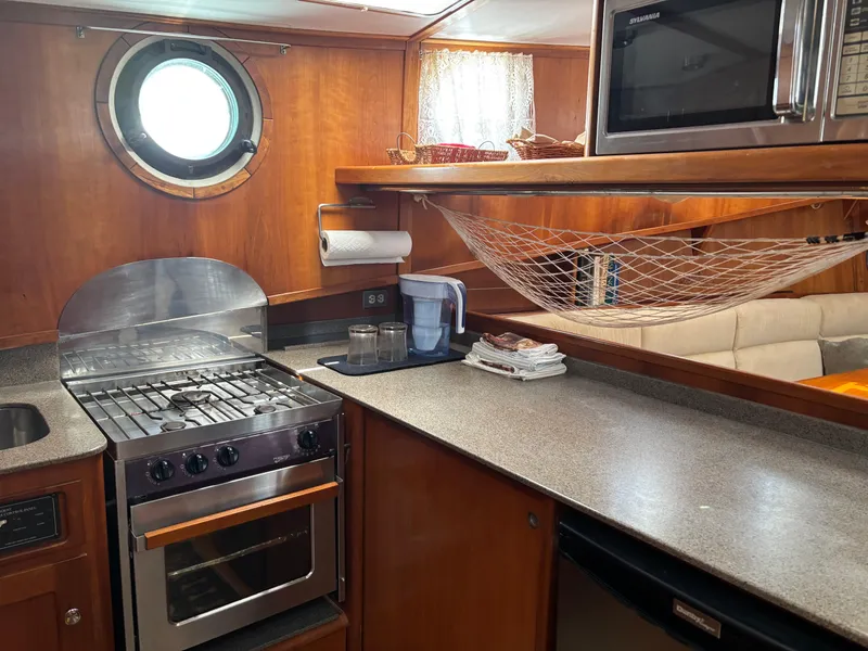 Slide: The Image of 1999 Diesel Duck Trawler kitchen with stove, microwave, and netting storage. - 29