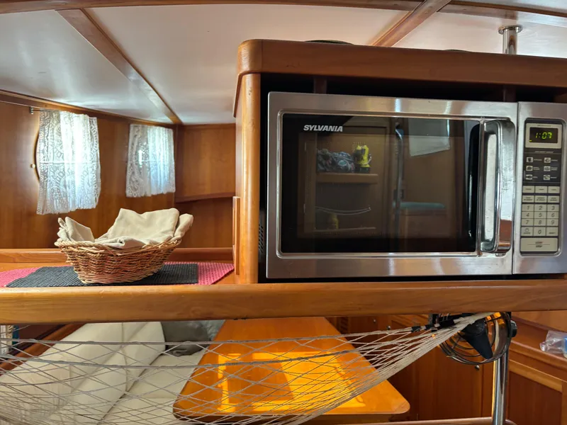 Slide: The Image of 1999 Diesel Duck Trawler interior with microwave, wicker basket, and cozy seating area. - 31