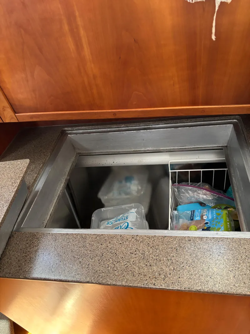 Slide: The Image of Built-in freezer in 1999 Diesel Duck Trawler, featuring organized storage and wooden cabinetry. - 33