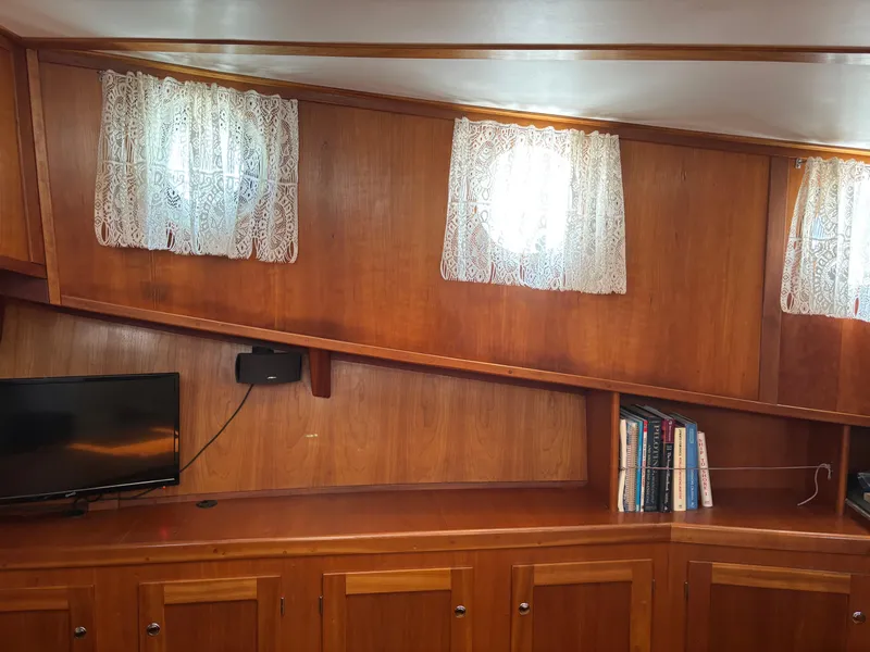 Slide: The Image of Interior of 1999 Diesel Duck Trawler with wood paneling, lace curtains, TV, and books. - 38