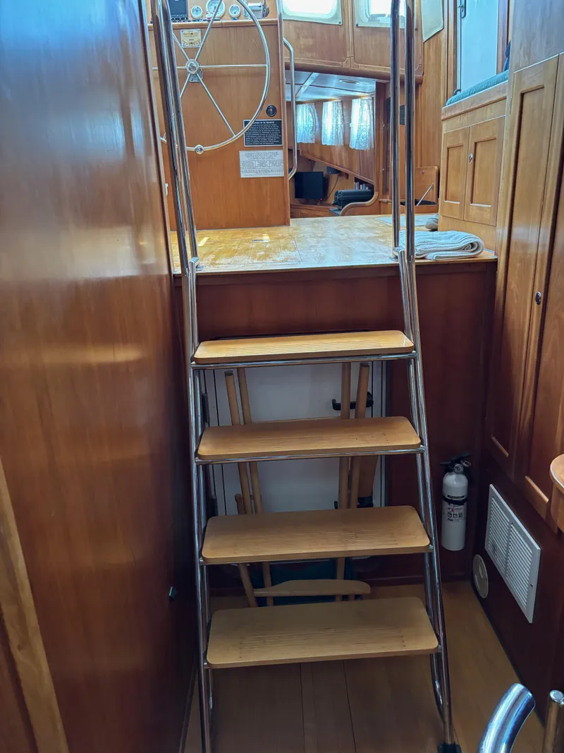 Slide: The Image of Wooden stairs inside a 1999 Diesel Duck Trawler, leading to the upper deck. - 43