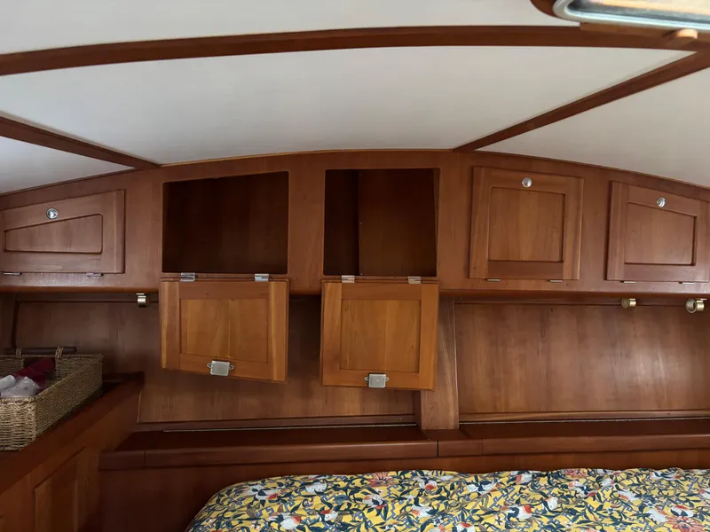 Slide: The Image of Wooden interior of 1999 Diesel Duck Trawler with storage cabinets and floral bedding. - 49