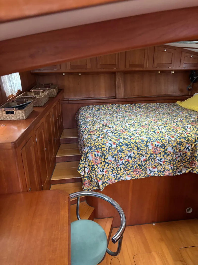 Slide: The Image of 1999 Diesel Duck Trawler cabin with floral bedspread, wooden cabinetry, and a chair. - 52