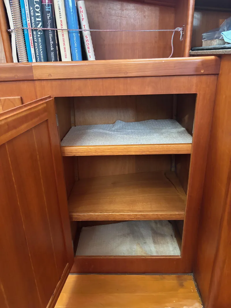 Slide: The Image of Wooden cabinet with open shelves on a 1999 Diesel Duck Trawler, books visible on top shelf. - 54