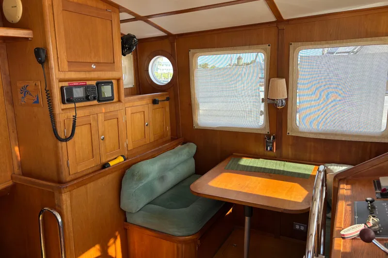 Slide: The Image of 1999 Diesel Duck Trawler interior with wooden cabinetry, seating, and navigation equipment. - 64