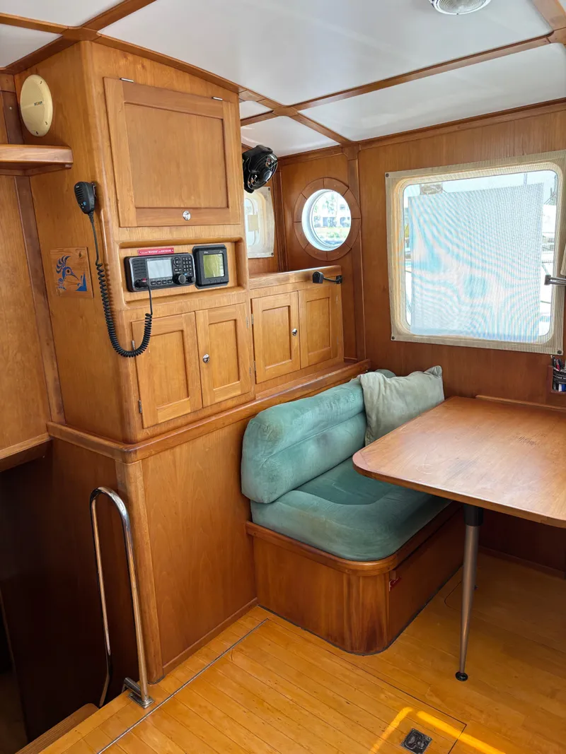 Slide: The Image of Interior of a 1999 Diesel Duck Trawler with wooden cabinetry and a cozy dining area. - 7