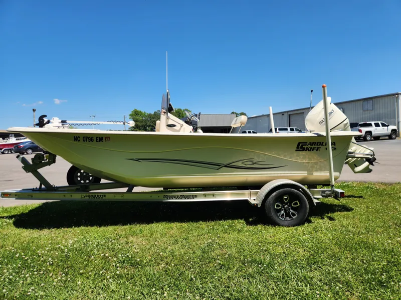 Slide: The Image of 2019 Carolina Skiff 198 DLV boat on trailer, parked on grass under clear blue sky. - 5