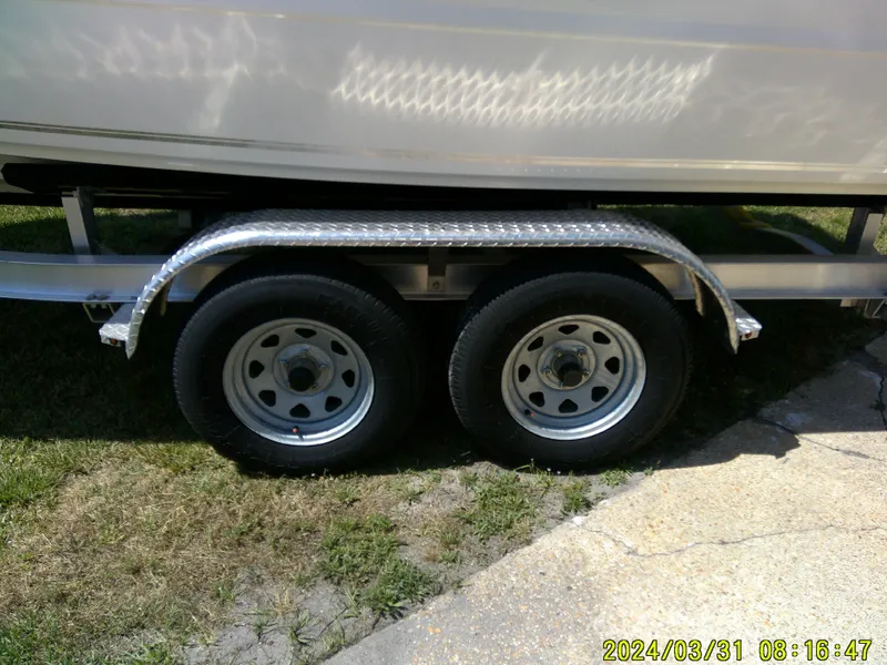 Slide: The Image of Trailer wheels of a 2024 Bulls Bay 200 CC boat on grass and pavement. - 4