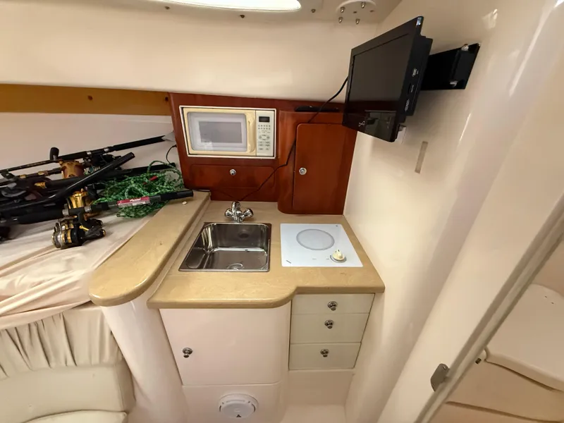 Slide: The Image of Compact kitchen area in a 2006 Intrepid 350 Center Console boat with sink, microwave, and TV. - 15