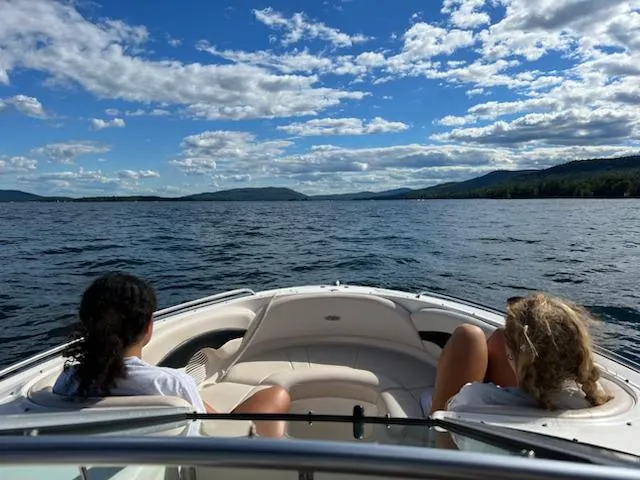 Slide: The Image of Two people relaxing on a 2000 Chaparral 230 SSi boat, enjoying a scenic lake view. - 3