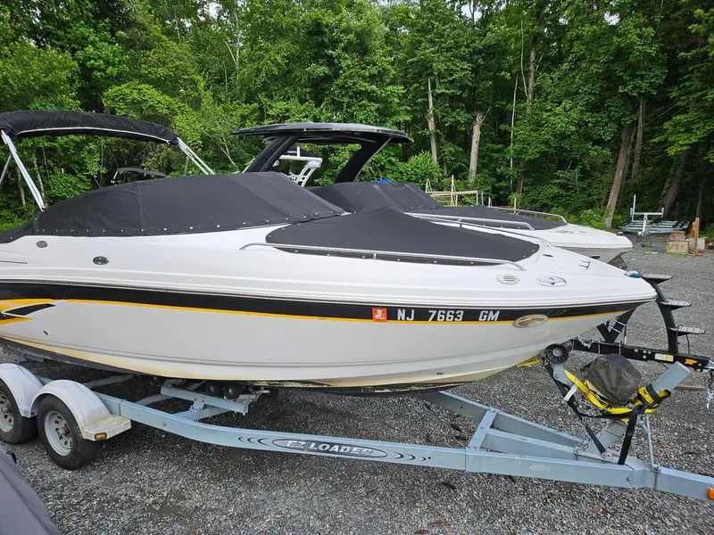 Slide: The Image of 2000 Chaparral 230 SSi boat on trailer, covered, surrounded by trees. - 9