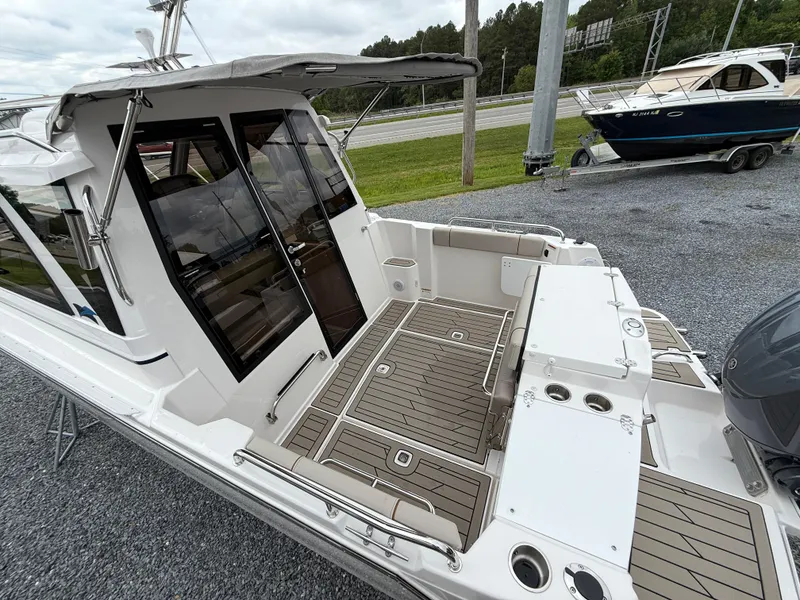 Slide: The Image of 2025 Cutwater C-248 Coupe boat with spacious deck and modern design, parked on gravel. - 4