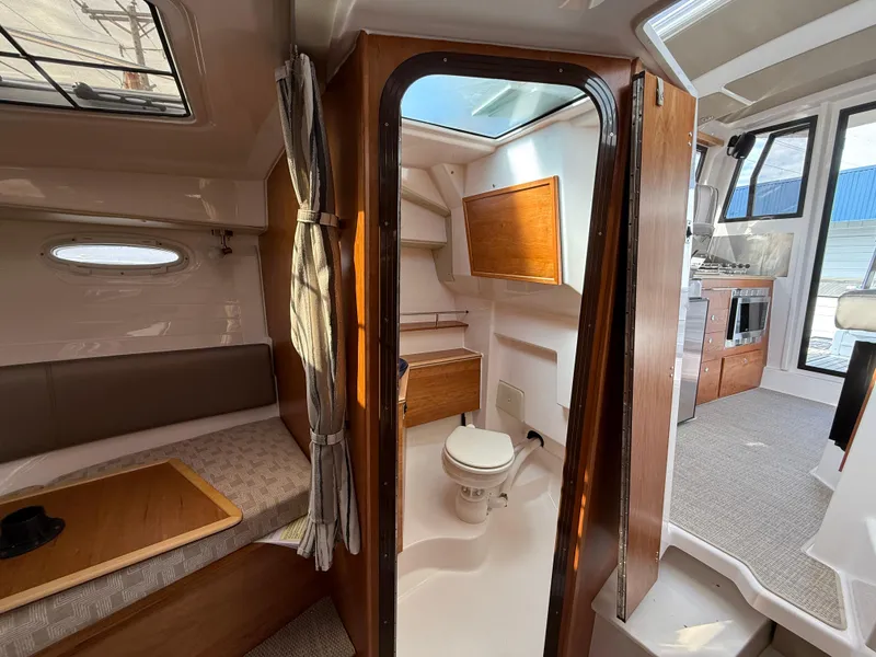 Slide: The Image of Interior of 2025 Cutwater C-288 Coupe, featuring cozy seating and compact bathroom. - 24