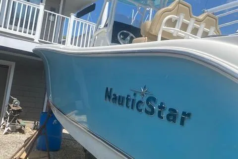 Slide: The Image of 2018 NauticStar 2602 Legacy boat with blue hull, docked near a house. - 1