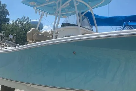 Slide: The Image of 2018 NauticStar 2602 Legacy boat with blue hull and canopy, docked outdoors. - 3