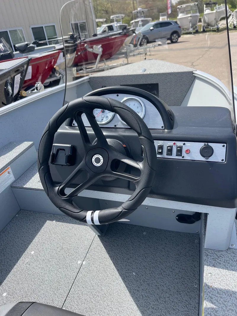 Slide: The Image of 2025 Lund 1600 Fury SS boat dashboard with steering wheel and control panel. - 4