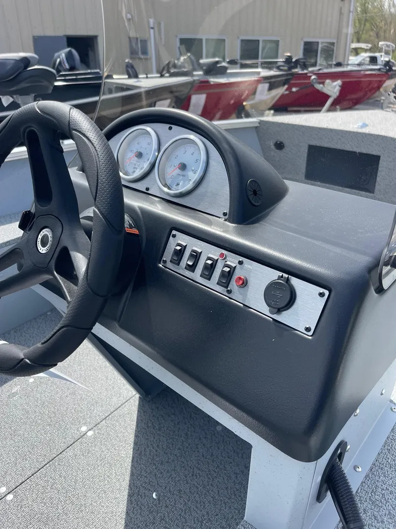 Slide: The Image of 2025 Lund 1600 Fury SS boat dashboard with steering wheel and control panel. - 5
