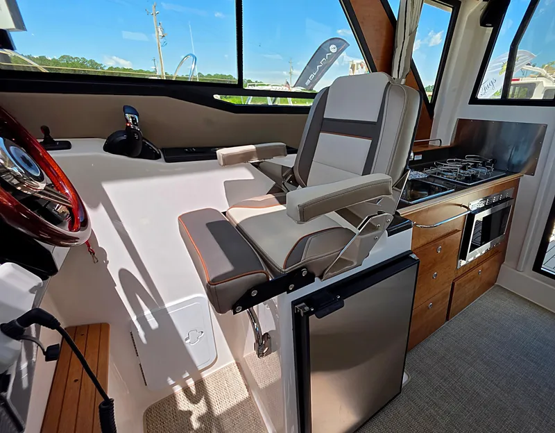 Slide: The Image of 2025 Cutwater C-288 Coupe interior with helm seat, kitchenette, and modern appliances. - 10