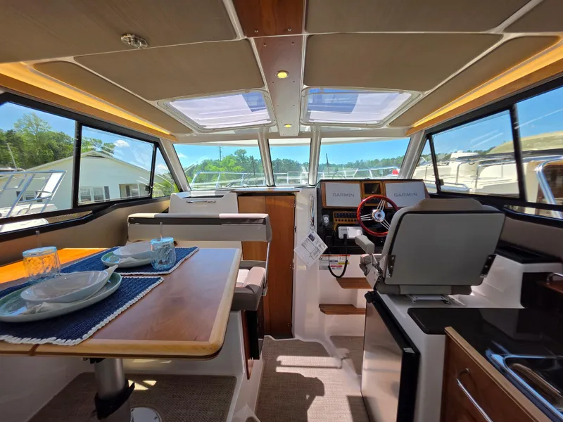 Slide: The Image of 2025 Cutwater C-288 Coupe interior with dining area, helm, and panoramic windows. - 11