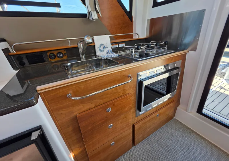 Slide: The Image of 2025 Cutwater C-288 Coupe kitchen with stove, sink, and oven in a compact design. - 6