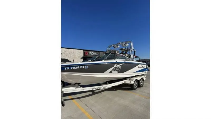 Slide: The Image of 2012 MasterCraft X45 boat on trailer, parked outdoors under clear blue sky. - 1