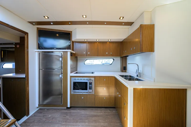 Slide: The Image of 2015 Cruisers Cantius yacht kitchen with modern appliances, wood cabinetry, and sleek design. - 19