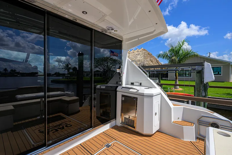 Slide: The Image of 2015 Cruisers Cantius yacht deck with outdoor kitchen and seating, under a clear blue sky. - 5