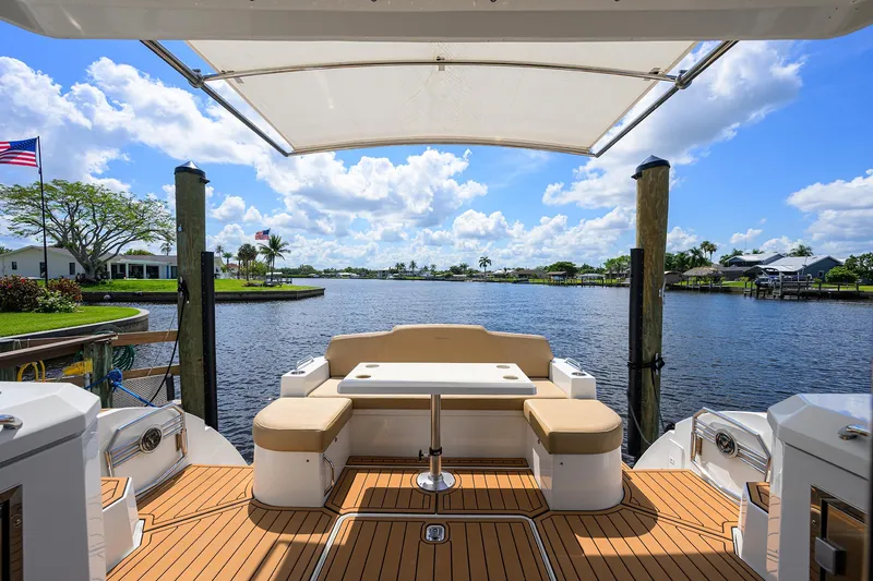 Slide: The Image of 2015 Cruisers Cantius yacht deck with seating, overlooking serene waterfront and blue sky. - 6