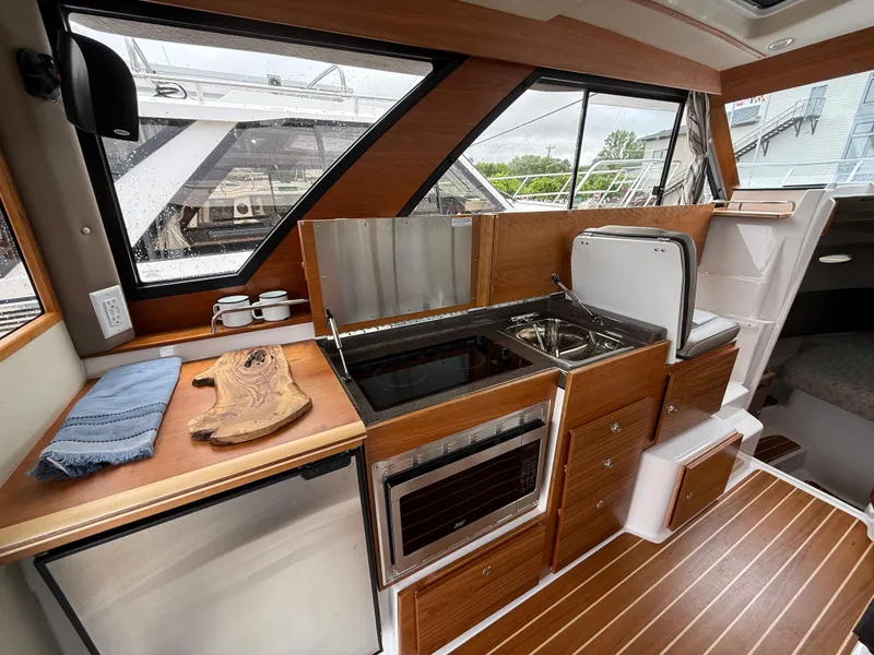 Slide: The Image of 2025 Cutwater C-32 C yacht interior kitchen with modern appliances and wooden cabinetry. - 13