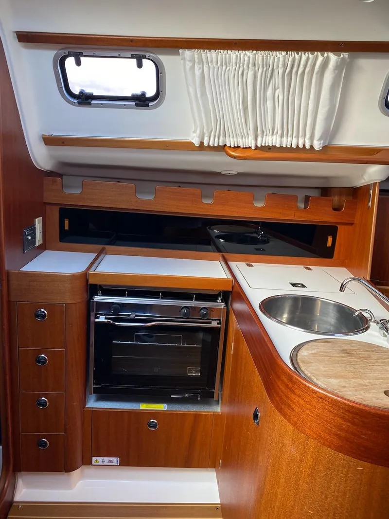 Slide: The Image of 2001 X-Yachts 332 interior kitchen with wood finish, oven, sink, and porthole window. - 21