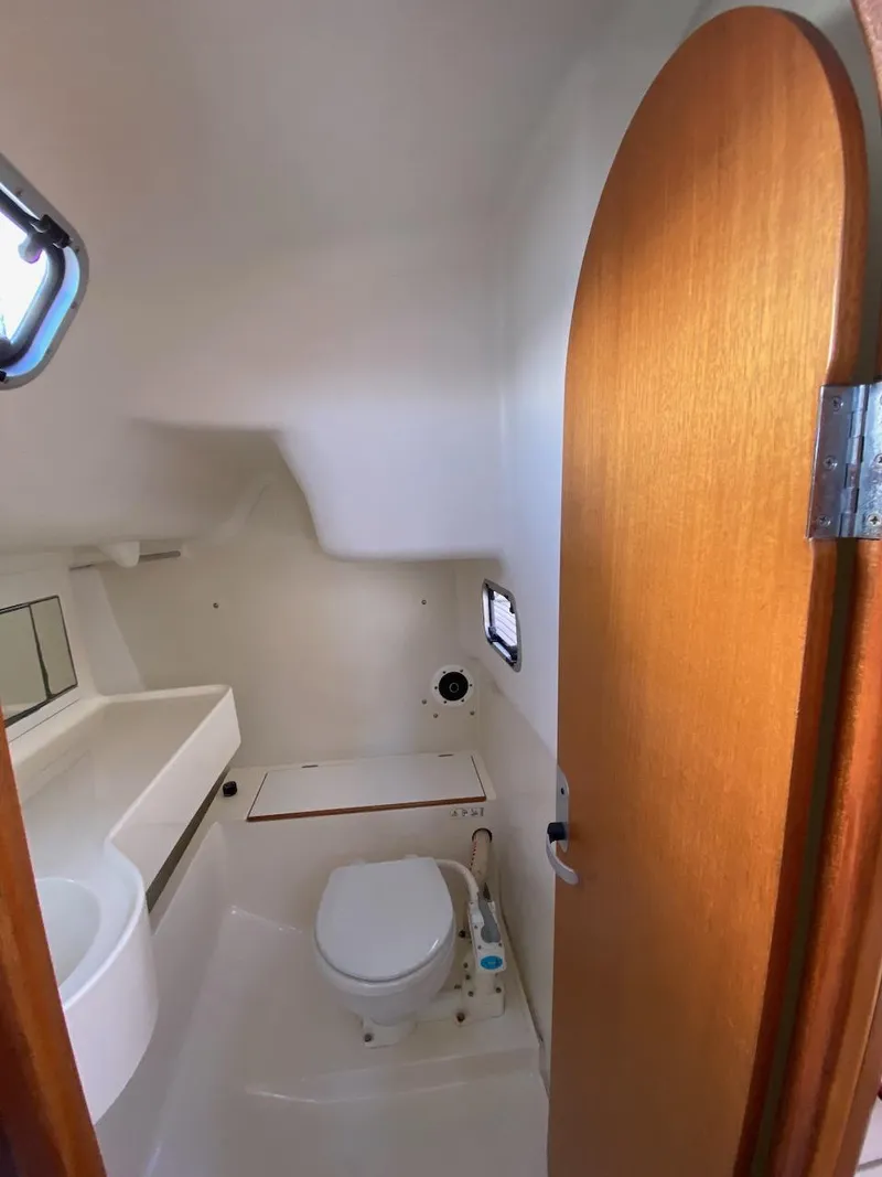 Slide: The Image of 2001 X-Yachts 332 bathroom with wooden door, compact toilet, and small window. - 35