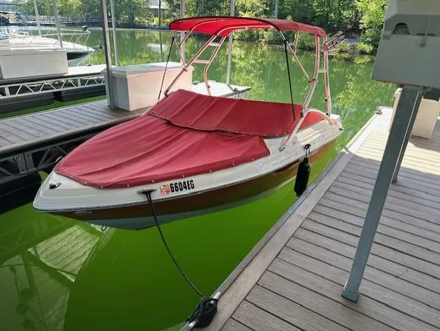 Slide: The Image of 2010 Four Winns H190 boat with red cover docked on green water. - 1